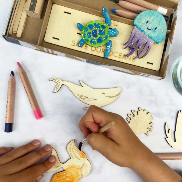 Watercolour pencils and paintbrush to colour the marine life wooden shapes